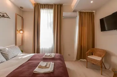 a bedroom with a bed with a chair and a television at Sofia Dream Apartment - Premium One Bedroom on Ekzarh Yosif by Flat Mаnager in Sofia