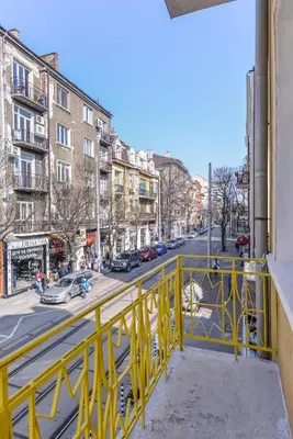 a yellow railing on a balcony looking down a city street at Chic 1BR with Terrace in Sofia City Center by Flat Mаnager in Sofia