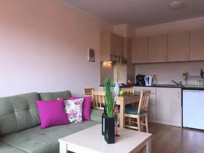 a living room with a couch and a table and a kitchen at Cedar Lodge 3/4 Apartment Paradise in Bansko