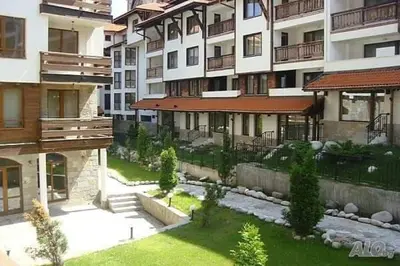 an apartment building with a garden in front of it at Cedar Lodge 3/4 Apartment Paradise in Bansko