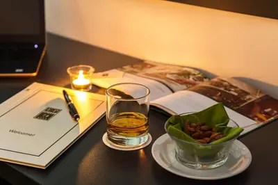 a table with a glass of whiskey and a bowl of nuts at Earth & People Hotel & SPA - Free Parking & Swimming Pool in Sofia