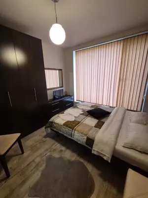 a bedroom with a bed and a large window at Апартамент Мегилукс in Blagoevgrad