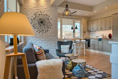 a living room with a couch and chairs and a kitchen at Apartment Audrey by SofiaSpot - central, metro to airport in Sofia