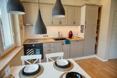 a kitchen with white cabinets and a table with chairs at Apartment Audrey by SofiaSpot - central, metro to airport in Sofia