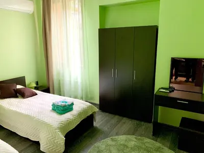 a green bedroom with a bed and a dresser at NIKI Apart in Sofia