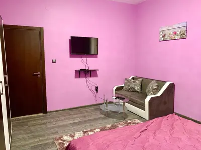 a pink room with a couch and a tv on a wall at NIKI Apart in Sofia