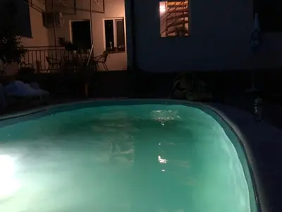 a swimming pool at night with a water fountain at Къща за гости с минерална вода 