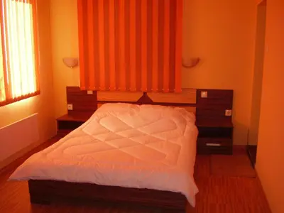 a bedroom with a bed with an orange curtain at Guest House Goranovi in Velingrad