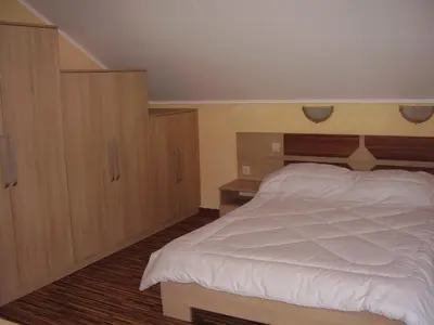 a bedroom with a white bed and wooden cabinets at Guest House Goranovi in Velingrad