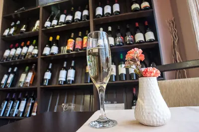 a wine glass and a vase on a table with wine bottles at C Comfort Hotel & Wellness in Hisarya
