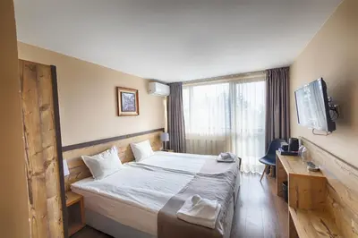 a hotel room with a bed and a desk and a television at Hotel Panorama Velingrad in Velingrad