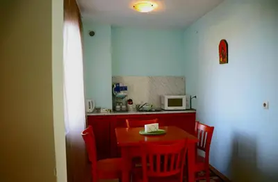 a kitchen with a table and chairs and a microwave at Family Hotel LILI in Bansko