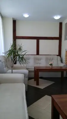 a living room with white couches and a table at Guest House Ela in Bansko