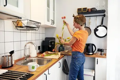 a woman standing in a kitchen holding flowers at Courthouse Apartments Slavi in Sofia