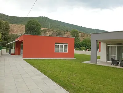 a building with a red wall and a grass yard at Villa Galiana in Simitli