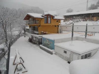 a house with snow on the roof of it at Къща за гости Суни Транс in Smolyan