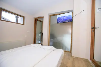 a bedroom with a white bed with a tv on the wall at Апартаменти Принц и Принцеса in Sandanski