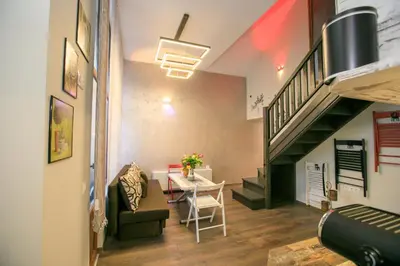 a living room with a table and a staircase at Апартаменти Принц и Принцеса in Sandanski