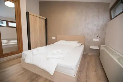a bedroom with a bed with white sheets and a window at Апартаменти Принц и Принцеса in Sandanski
