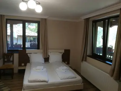 a bedroom with two beds and two windows at Слънчевата къща in Kovachevitsa