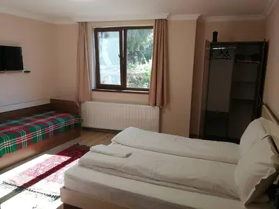 a living room with two beds and a window at Слънчевата къща in Kovachevitsa