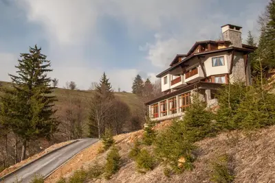 a house on the side of a hill next to a road at The Poppies House in Pamporovo