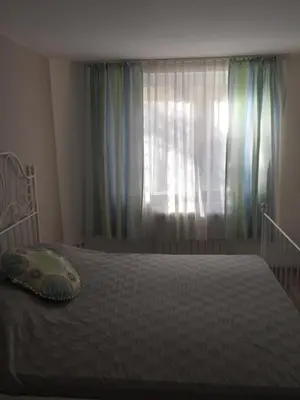 a bedroom with a bed and a window with curtains at Apartment Button in downtown in Sofia