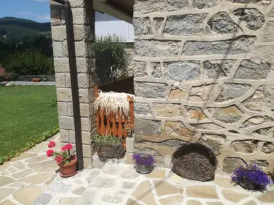 a stone wall with a bench and flowers on a patio at Радкината къща in Koprivshtitsa