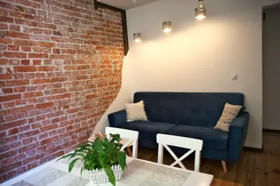 a living room with a blue couch against a brick wall at The FlyingTheatre Suites in Plovdiv