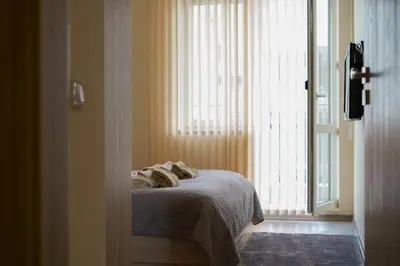 a bedroom with a bed next to a large window at The Place -Apartments in Plovdiv, with private parking in Plovdiv