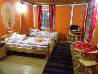 two beds in a room with orange walls and a television at Стаи за гости Дончо Войвода in Koprivshtitsa