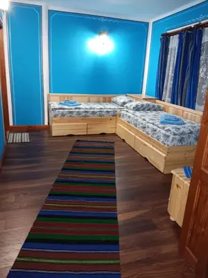 two beds in a room with a blue wall at Стаи за гости Дончо Войвода in Koprivshtitsa