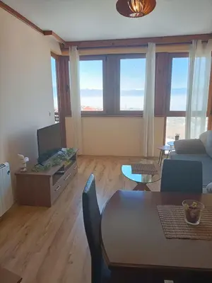 a living room with a table and a couch and a tv at Private Apartment Maxim in Bansko