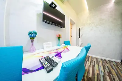 a room with a desk with a television and blue chairs at Sofia Colour Life Apartment -No Window Apartment in Sofia