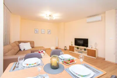 a living room with a table and chairs and a television at Domus Apartments Grand with Parking in Plovdiv