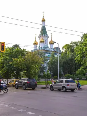 a building with a tower with gold domes and cars on a street at CACAO Studio next to Crystal Garden and Russian Church by Flat Mаnager in Sofia