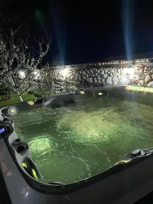 a bath tub with green water at night at Къща за гости Александра in Dobrinishte