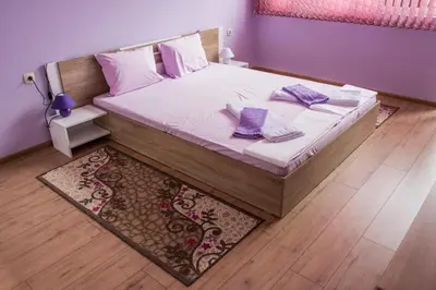 a bedroom with a bed with purple pillows and a rug at Apartment Petya in Velingrad