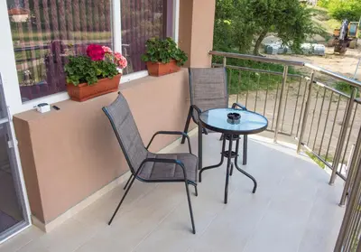 two chairs and a table on a balcony with flowers at Apartment Petya in Velingrad
