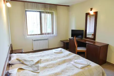 a bedroom with a bed and a desk and a computer at Lovna sreshta in Bansko