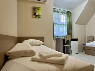 a bedroom with a bed and a desk and a window at Хостел Атлас - Hostel Atlas in Blagoevgrad
