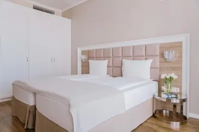 a white bedroom with a large bed and a table at Impresamente Art Hotel in Sofia