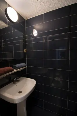 a bathroom with black tiled walls and a sink at Design Apartment in Sofia top city center in Sofia