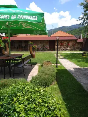 a patio with a table and a green umbrella at СТАР МЕРАК in Ribarica
