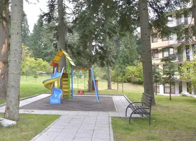 a playground with a slide and a bench in a park at VIVA Flora apartment 607A in Borovets