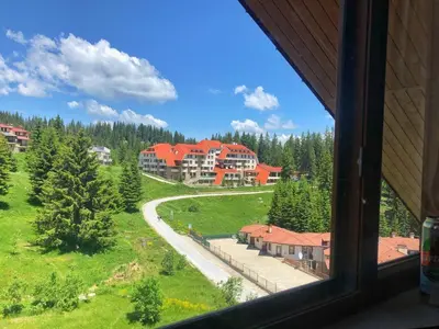 a view of a large house from a window at Ски апартамент, студио Хрис, Лъки Пампорово in Pamporovo