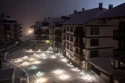 a group of buildings at night with snow on the roofs at NEXT TO GONDOLA Stylish and Charming apartment in Bansko