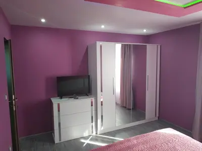 a bedroom with purple walls and a tv and a mirror at ВИЙГ in Sapareva Banya