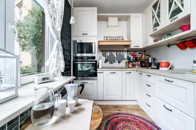 a kitchen with white cabinets and a wooden table at 3BDR The Hadjis - City Center Flat in Sofia
