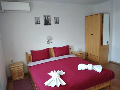 a bedroom with a red bed with two white bows at Holiday guest house KEMO in Sapareva Banya